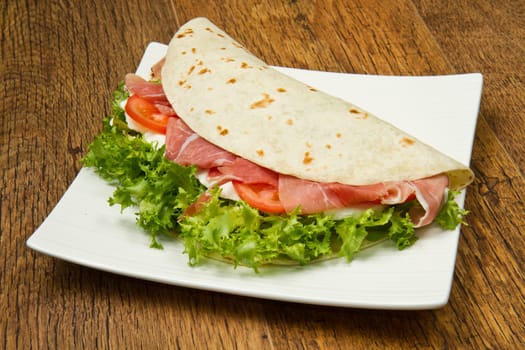 italian piadina with ham, fresh salad and mozzarella cheese