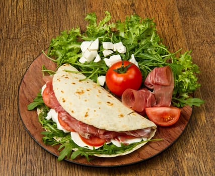 italian piadina with ham, fresh salad and mozzarella cheese