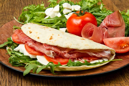 italian piadina with ham, fresh salad and mozzarella cheese