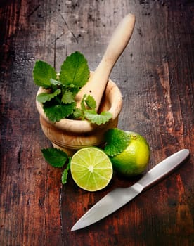 Mortar, Limes and Peppermint on a wood Background. Ingredients for Caipirinha and Mojito Cocktails and other drinks