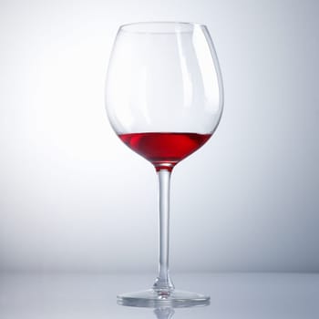 Half drunk Wine Glass on a light blue background with reflexion