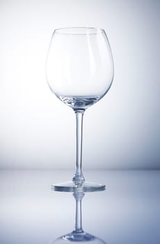 Empty wine glass with reflexion and a blue background