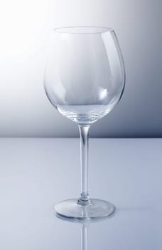 Empty wine glass with reflexion and a blue background