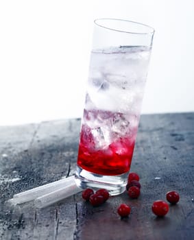 Cocktail Drink with grenadine standing on straws on a wooden vintage bar.