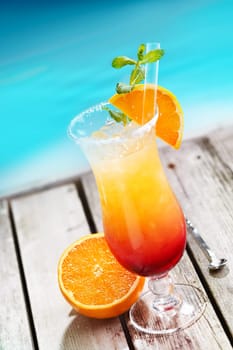 Sex on the beach Cocktail on wooden planks in front of a blue swimming pool or the ocean. For Drinkable Concepts visit my Portfolio.