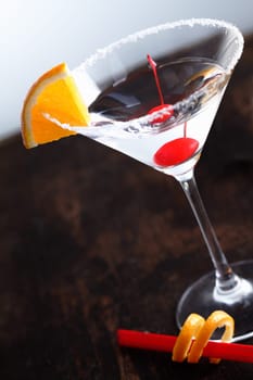 Dry Martini with a cherry and an slice of orange fruit on an aged background