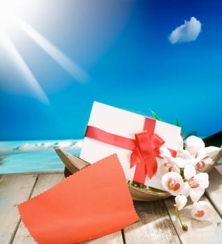 Voucher in a palm bowl with a bow at a deck in front of the deep blue pacific ocean and a shiny sun. With copyspace for your own Text and messages