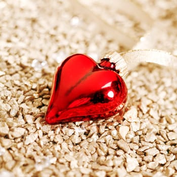 Romantic background of a shiny red Christmas heart ornament with shallow dof