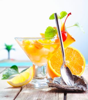 Colourful exotic fruit cocktail of fresh tropical fruits presented with a serving spoon in a rest at an upmarket resort