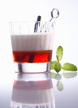 Low angle view of a layered alcoholic cocktail in a tumbler with reflection, background graduating white to grey