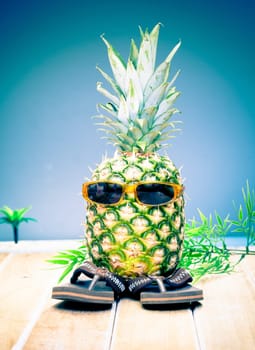 Comical character of a cool dude pineapple in his trendy sunglasses and slip slops out enjoying the tropical sunshine