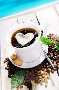 Coffee in a Cafe near the beach with a heart of cream and coffee beans around. Standing on a Table at a Coffee Bar at the coastline near the beach for your Travel cuisine concepts.