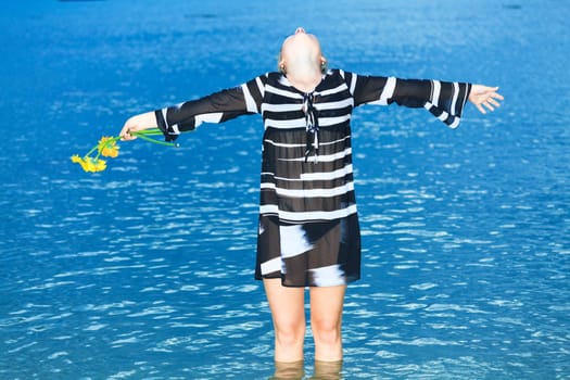 Beautiful woman with flowers in the sea