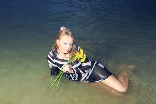 Beautiful woman with flowers in the sea