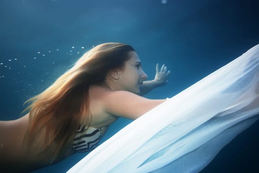 Young woman as a mermaid swimming underwater