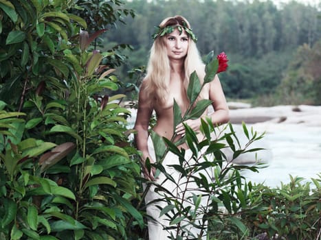 Beautiful woman as a forest nymph on the river