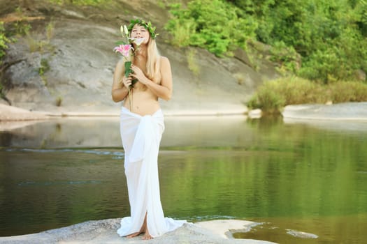 Beautiful woman as a forest nymph on the river