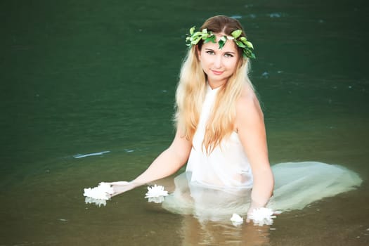 Beautiful woman as a forest nymph on the river