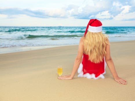 Miss Santa sitting near the ocean with glass of wine