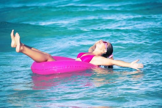 Funny woman relaxing on pink inner tube