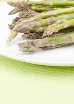 Spears of Fresh Uncooked Asparagus on White Plate - Shallow Depth of Field