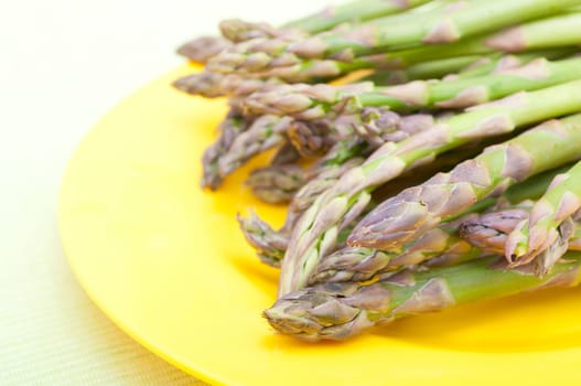 Spears of Fresh Uncooked Asparagus on Yellow Plate - Shallow Depth of Field
