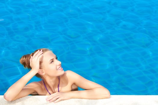 Cute girl in swimming pool looking at copy space