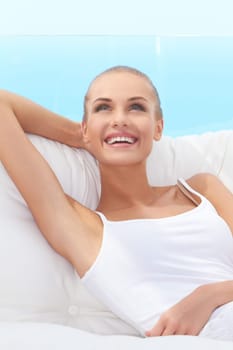 Adorable woman smiling broadly and looking off camera while seated on a white couch