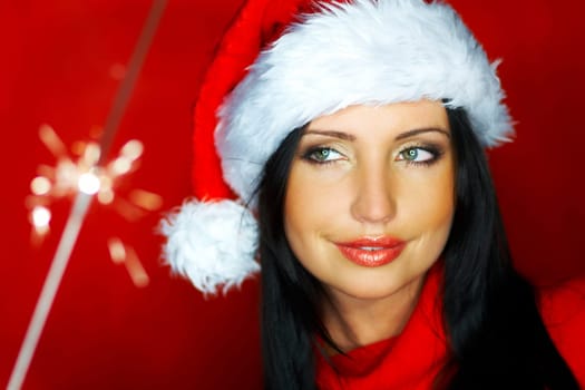 Portrait of beautiful brunette woman wearing santa claus hat on red background