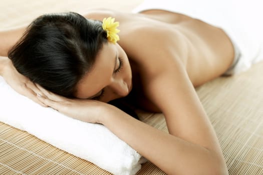 Portrait of Fresh and Beautiful brunette woman laying on bamboo mat around yellow flowers
