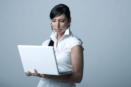 Beautiful and sexy brunette business woman with laptop computer. She is isolated on clear background
