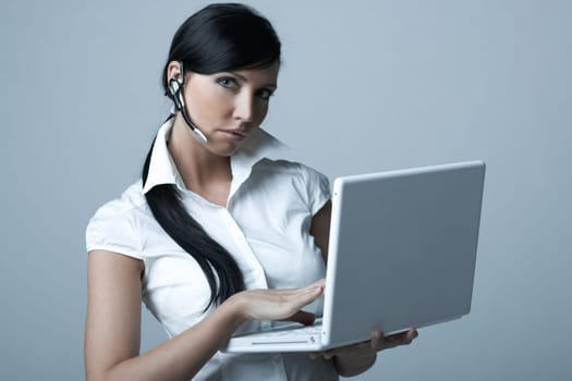 Beautiful brunette business woman with wireless headset and laptop computer isolated on clear background