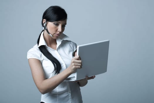 Beautiful and sexy brunette business woman with laptop computer. She is isolated on clear background