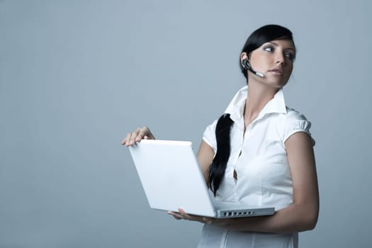 Beautiful brunette business woman with wireless headset and laptop computer isolated on clear background