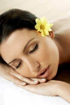 Portrait of Fresh and Beautiful brunette woman laying on bamboo mat around yellow flowers
