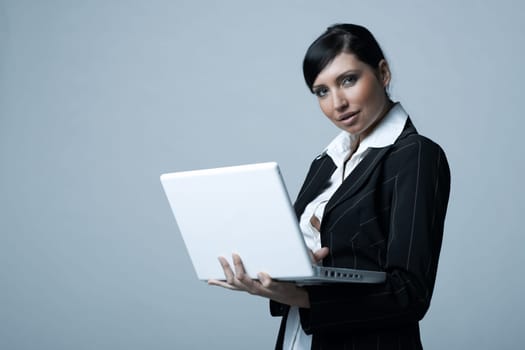 Beautiful and sexy brunette business woman with laptop computer. She is isolated on clear background