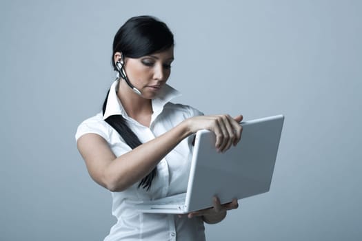 Beautiful and sexy brunette business woman with laptop computer. She is isolated on clear background