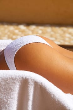 Sexy womans body part in bikini during sunbath laying on deckchair