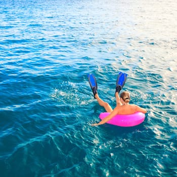Funny woman in fins on inflatable tube