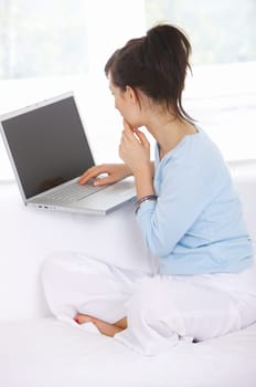 Young woman is on couch and working on laptop