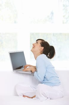 Young woman is on couch and working on laptop