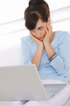 Young woman is on couch and working on laptop