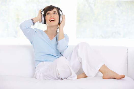 Young woman on couch and listen to the music