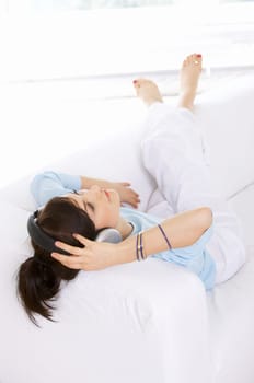 Young woman on couch and listen to the music