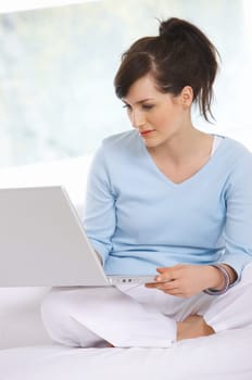 Young woman is on couch and working on laptop