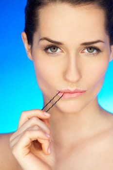 Portrait of beautiful woman with hairpin in mouth