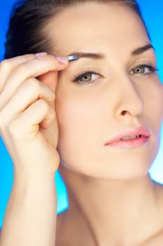 Portrait of beautiful woman with tweezers