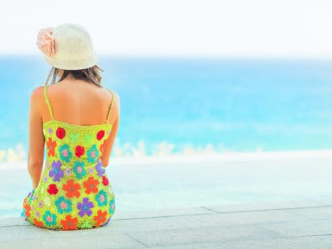 Rear view of woman sitting on the edge of swiming pool