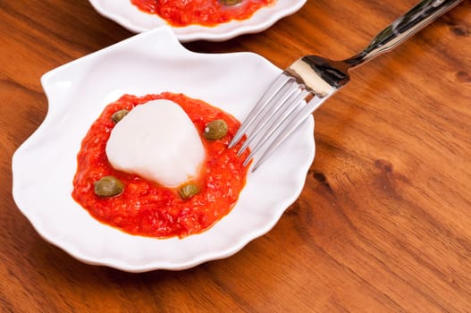 Meat of a scallop on paprika puree with green capers