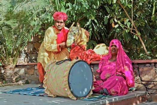 Landscape portrait of a Colorful couple travelling puppetier musician resting in the shade before a performance